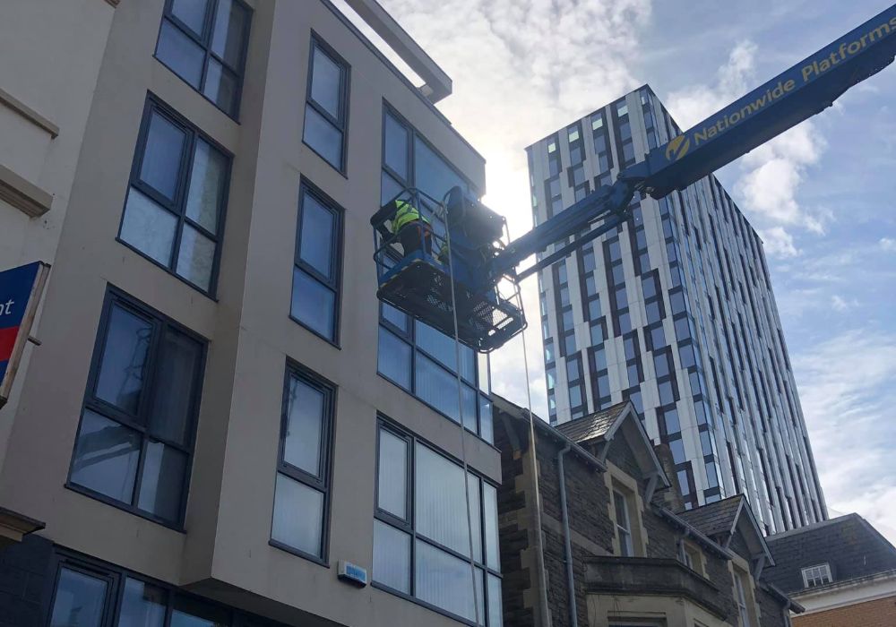 Person Cleaning Building High Up On Lift